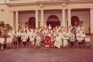 A photo taken with the Bishop, residents and the Sisters in front of the Chapel